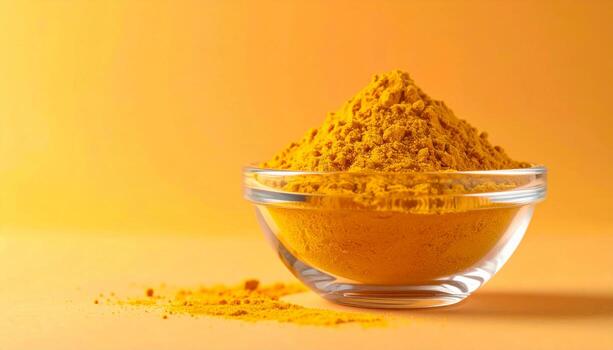 Fine orange curcumin powder in a glass bowl on an orange background