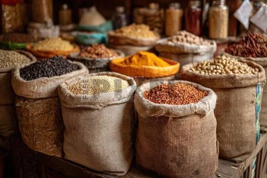 Hessian sacks of dried herbs and spices stacked at an open-air market stall with no readable signage