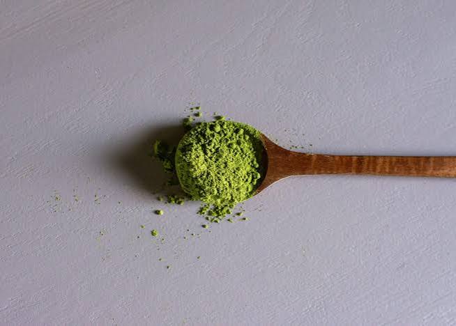 Fine green botanical powder on wooden spoon